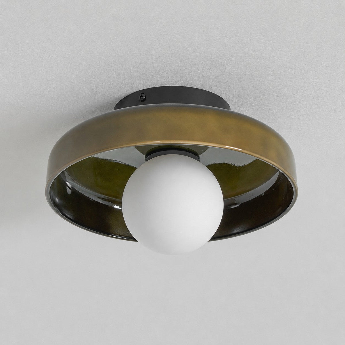 The Clérachic olive-brown glass-disc light switched off, its frosted white globe pale against a grey ceiling.