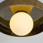 Close view of the lit white globe glowing inside the olive glass disc of this Clérachic ceiling light.