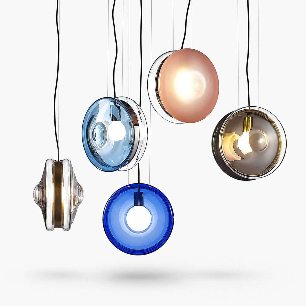 Five Clérachic glass pendants hanging at different heights on a white backdrop, in dark blue, light blue, pink, clear and smoky grey.