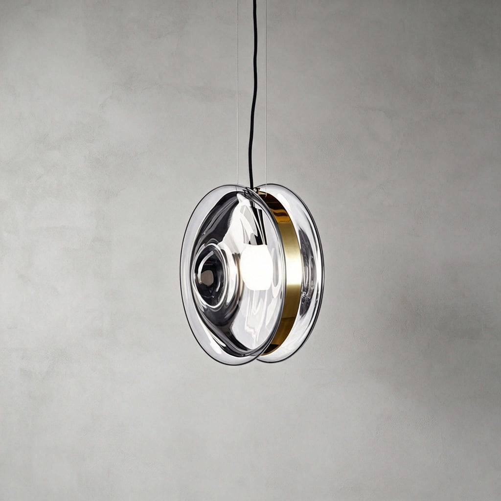 This Clérachic glass disc pendant in clear glass, with a brass band around the rim and the round bulb visible inside.