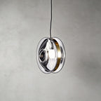 This Clérachic glass disc pendant in clear glass, with a brass band around the rim and the round bulb visible inside.