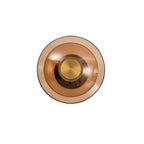 Front view of a Clérachic wall light with an amber glass disc, a smaller inner dish and a gold cap, on white.