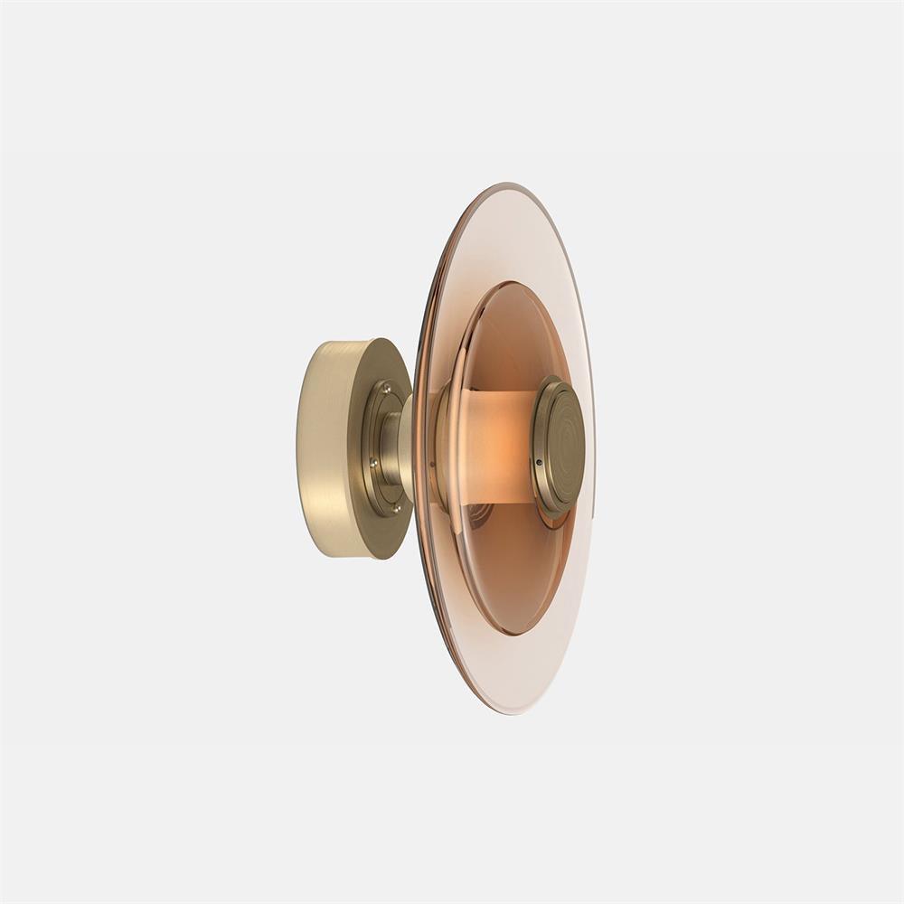 A Clérachic wall light with an amber glass disc and a gold back plate, seen from the side on a pale grey backdrop.