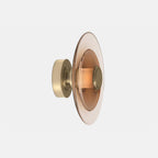 A Clérachic wall light with an amber glass disc and a gold back plate, seen from the side on a pale grey backdrop.