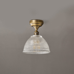 Unlit, the clear grid-patterned glass dome of this Clérachic ceiling light hangs from a short antique brass stem.