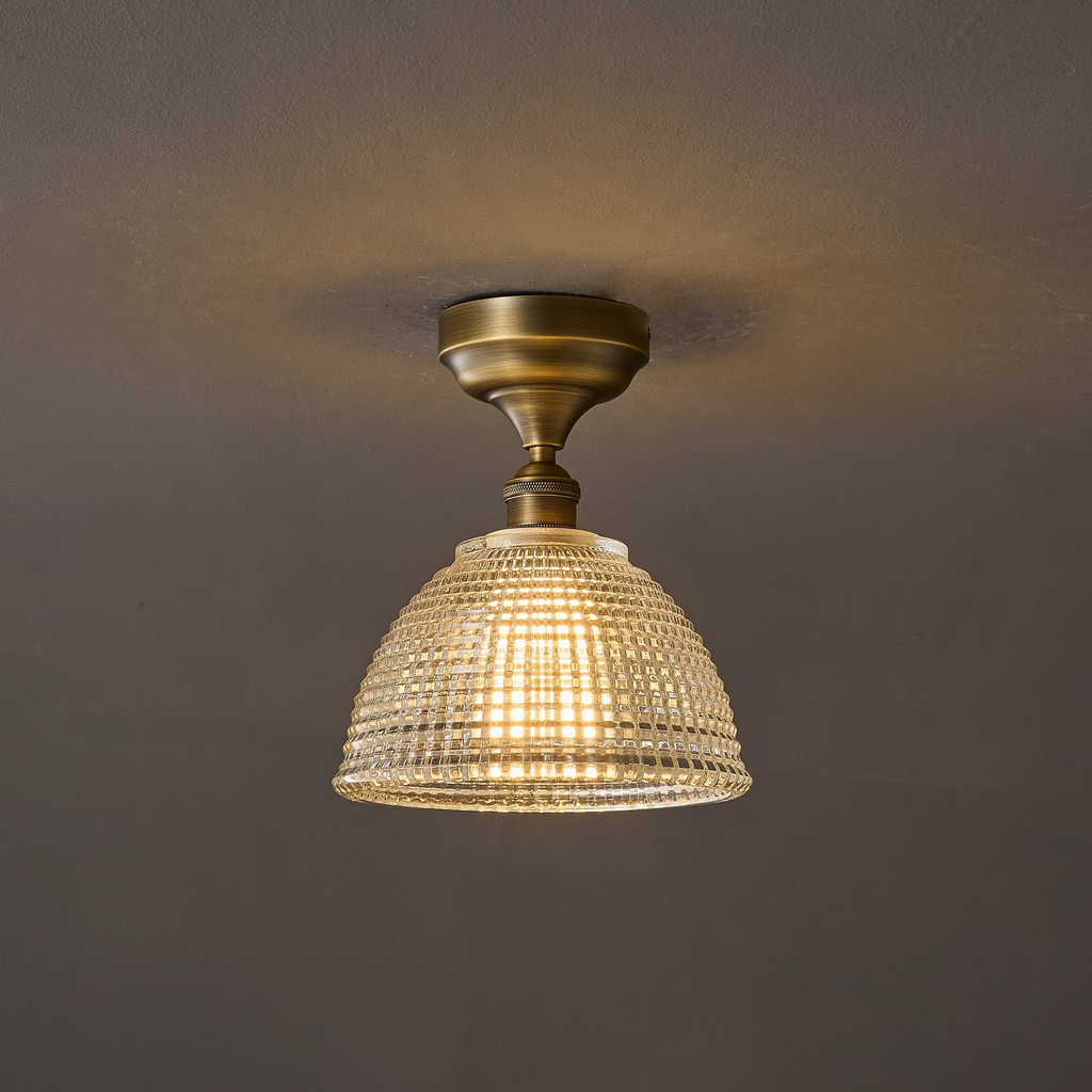 This Clérachic ceiling light switched on, its brass canopy casting a soft ring of light on the ceiling above the glowing dome.
