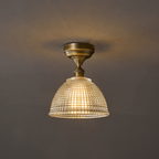This Clérachic ceiling light switched on, its brass canopy casting a soft ring of light on the ceiling above the glowing dome.