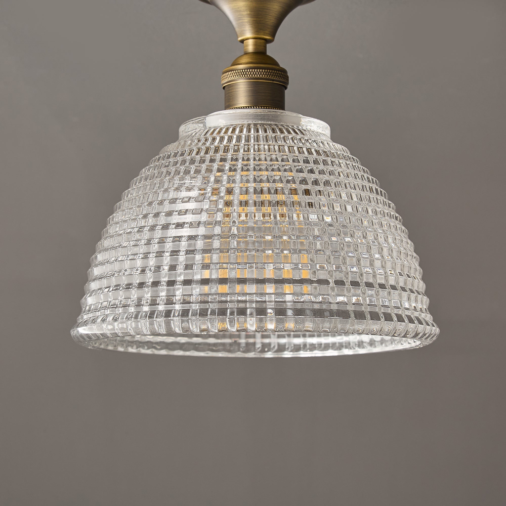 The clear ribbed glass dome of this Clérachic ceiling light, seen from below with its brass stem and white collar at the top.
