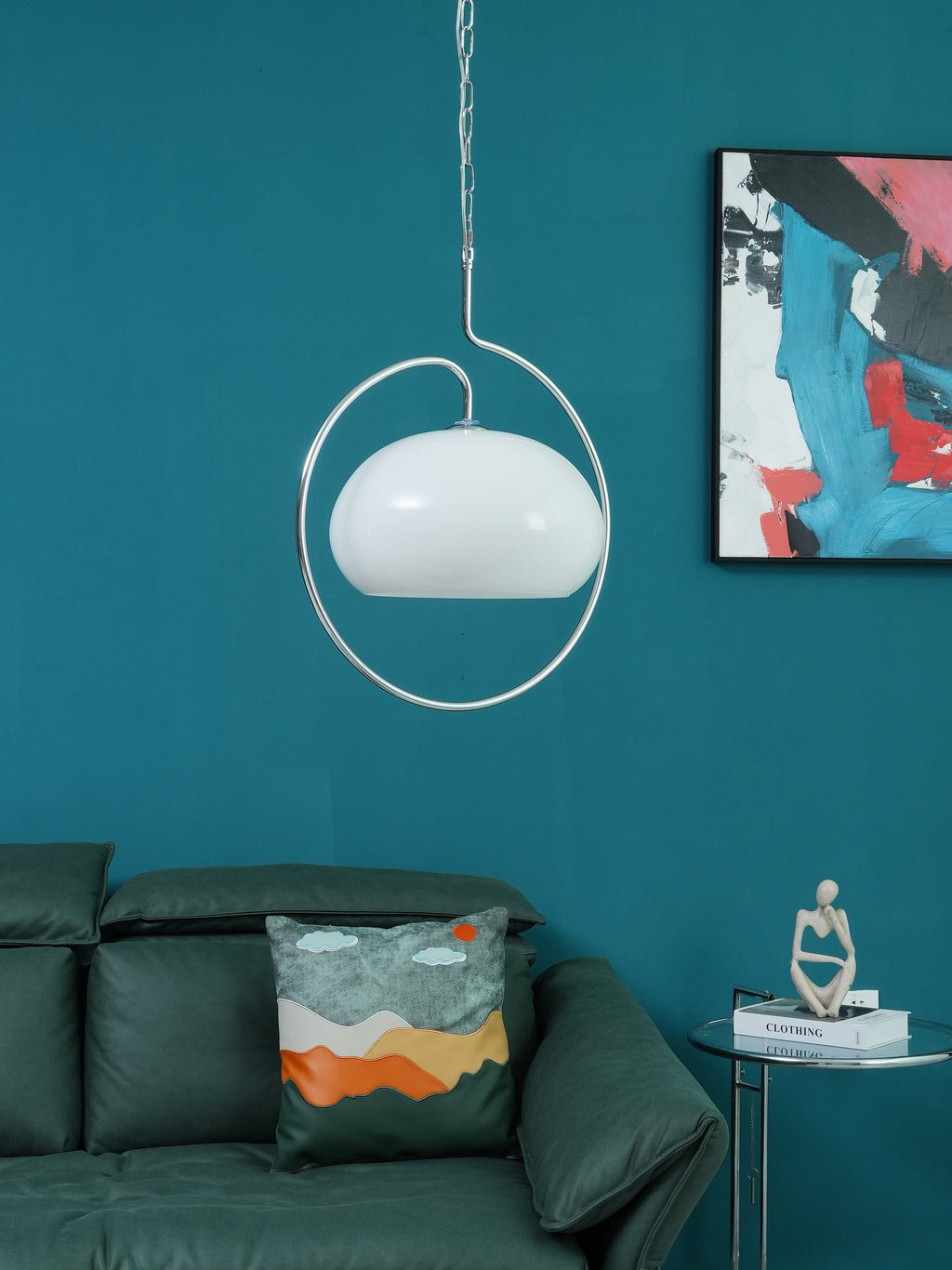 Unlit white version of this Clérachic pendant inside its chrome ring, against a teal wall with a colourful abstract print.