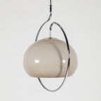 Clérachic glass dome pendant in a soft grey-taupe tone, tilted inside its chrome ring against a pale background.