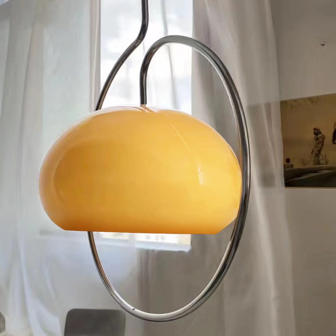 Brown glass Clérachic pendant with a glossy dome and chrome ring, backed by a window with sheer curtains and a framed print.