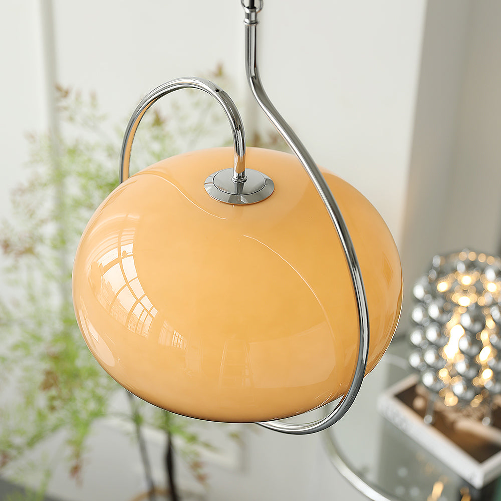 Close view of the brown glass dome on this Clérachic pendant, with its chrome collar and curved arm, and a bead-shaped lamp behind.