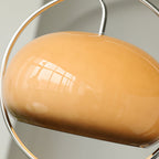Close view of the glossy brown glass dome of this Clérachic pendant, reflecting a window, with the chrome ring curving around it.