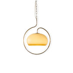 Pale yellow glass Clérachic pendant with a champagne-coloured ring, hanging on a fine chain against white.