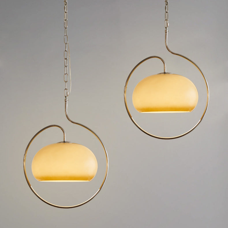 Pair of Clérachic pendants with yellow-cream glass domes in champagne-toned rings, hung at different heights against a grey backdrop.
