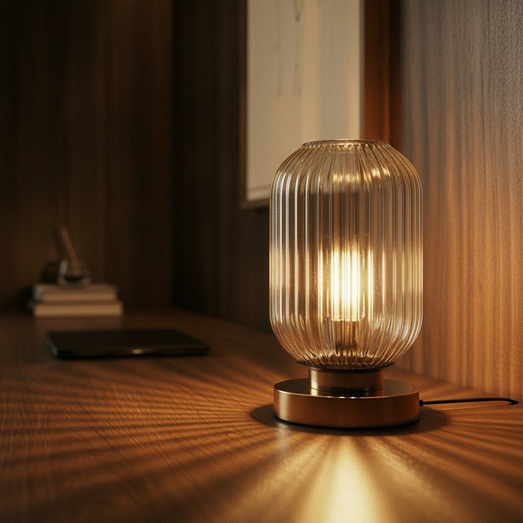 Clérachic ribbed glass dome table lamp in a clear tone, lit close on a walnut desk beside books and a phone.