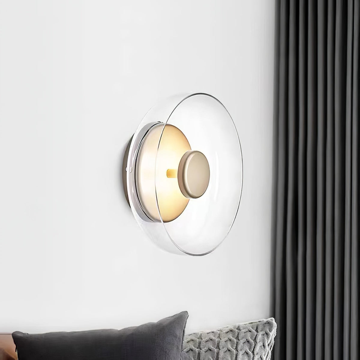 Mounted on a white wall beside a dark grey curtain, this Clérachic wall light has a clear glass dome and a brass centre knob.