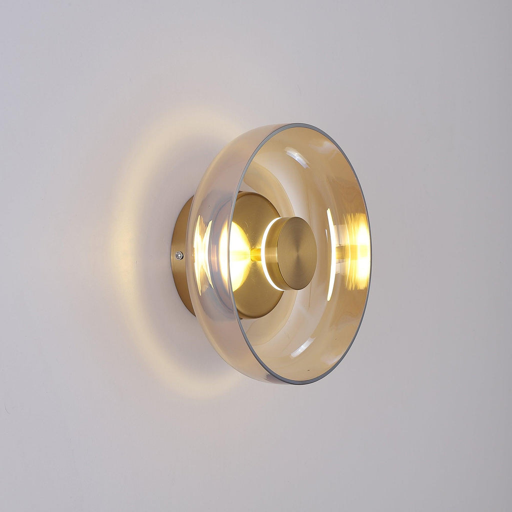 Side-on, this Clérachic wall light throws a halo of warm light round a clear glass dome and a brass wall plate.