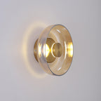 Side-on, this Clérachic wall light throws a halo of warm light round a clear glass dome and a brass wall plate.