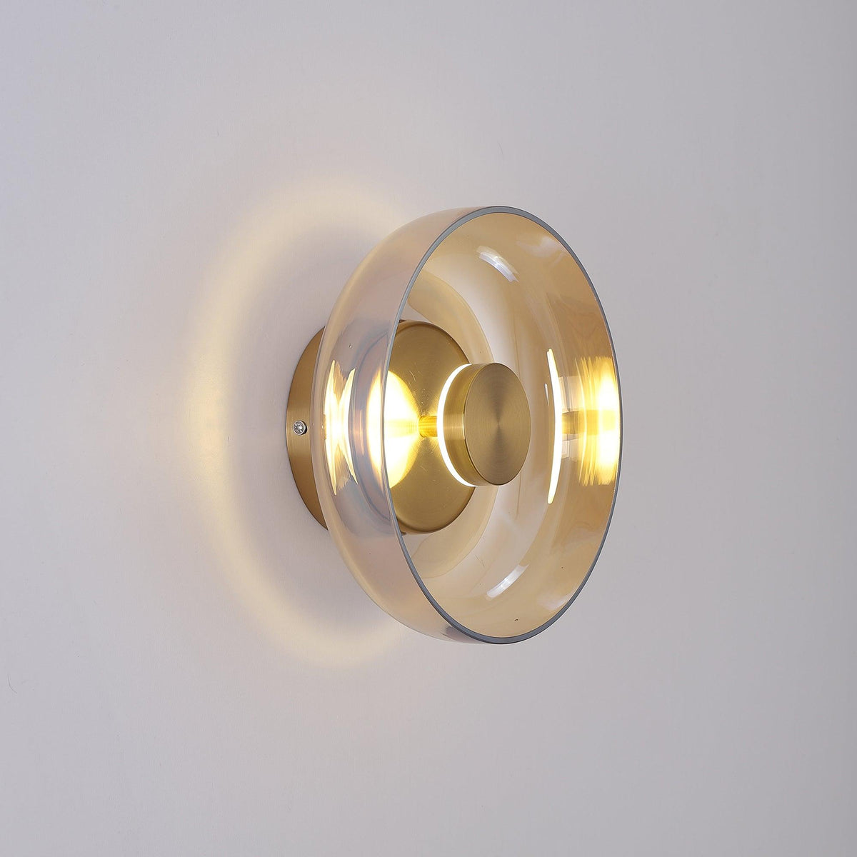 Side-on, this Clérachic wall light throws a halo of warm light round a clear glass dome and a brass wall plate.