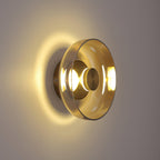 Warm light spreads across a taupe wall from this Clérachic wall light, whose pale amber glass dome sits on a brass back plate.