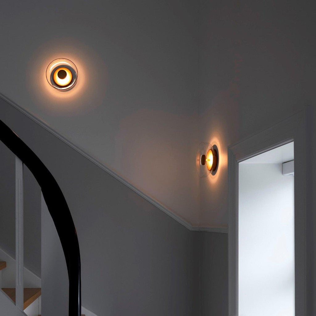 Two Clérachic wall lights glow warm at the top of a dark grey stairwell, one on each wall.