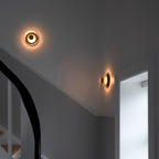 Two Clérachic wall lights glow warm at the top of a dark grey stairwell, one on each wall.