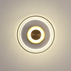 A Clérachic wall light on a cream wall, with a wide halo of warm light and a smoky glass dome around a glowing brass disc.