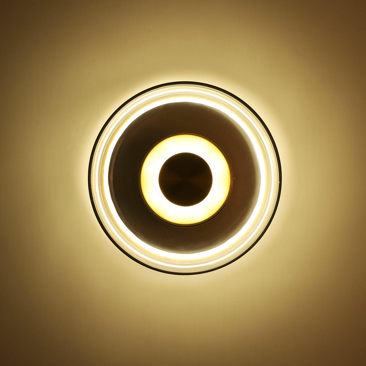 Against a deep amber-brown wall, this Clérachic wall light glows in the dark, its glass rim and brass disc ringed with light.