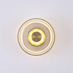 Lit front view of an amber glass Clérachic wall light, with a bright glowing ring beneath the glass and a brass centre disc.