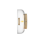 Side profile of this Clérachic wall light on white, with a shallow clear glass dome, a brass stem and a round brass wall plate.