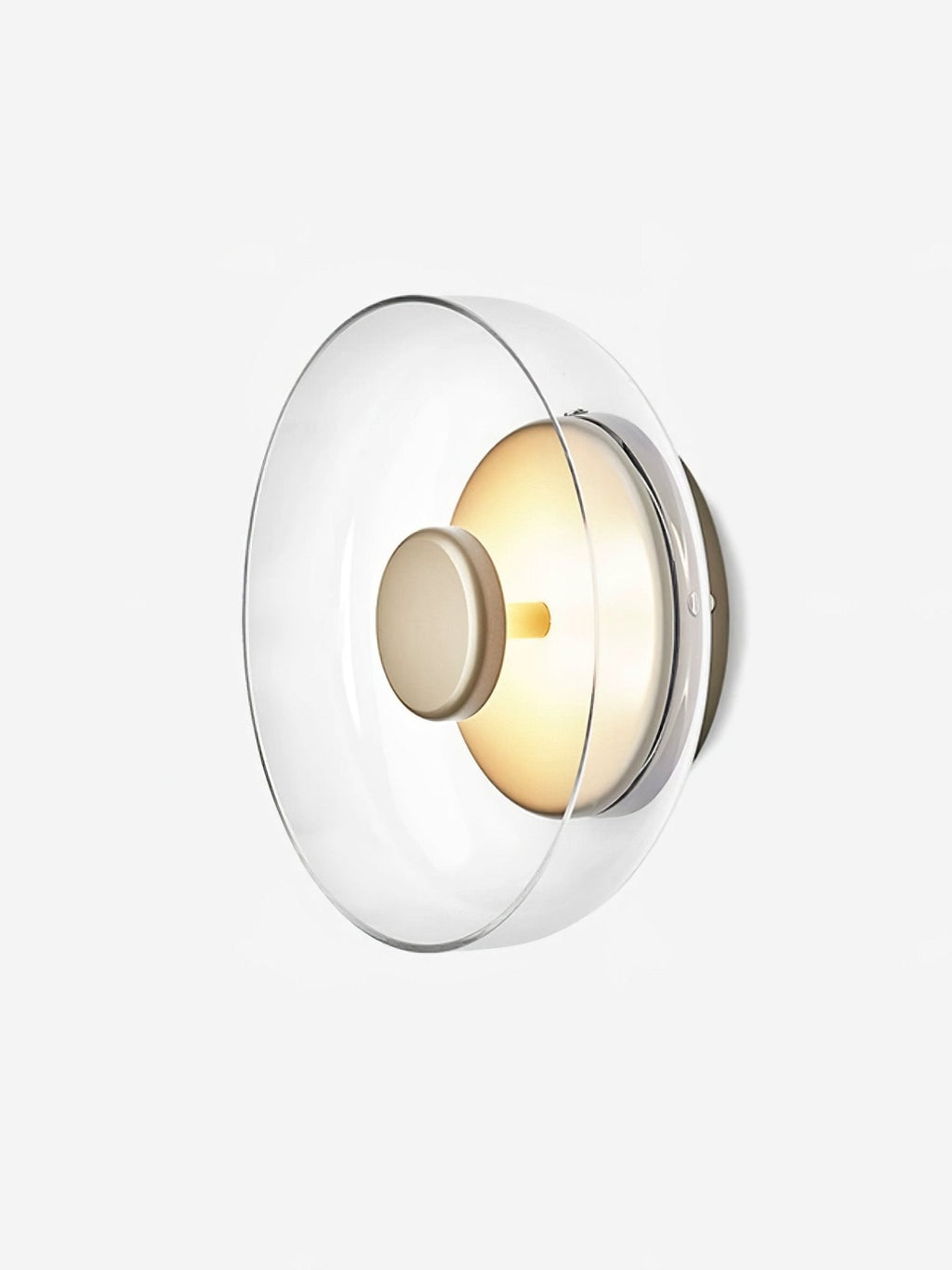 Angled view of this Clérachic wall light on white, with a clear glass dome and a brass disc over a softly glowing interior.
