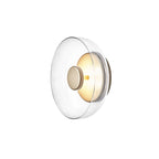 Three-quarter view of this Clérachic wall light with a clear glass dome and a brass disc on a white background.