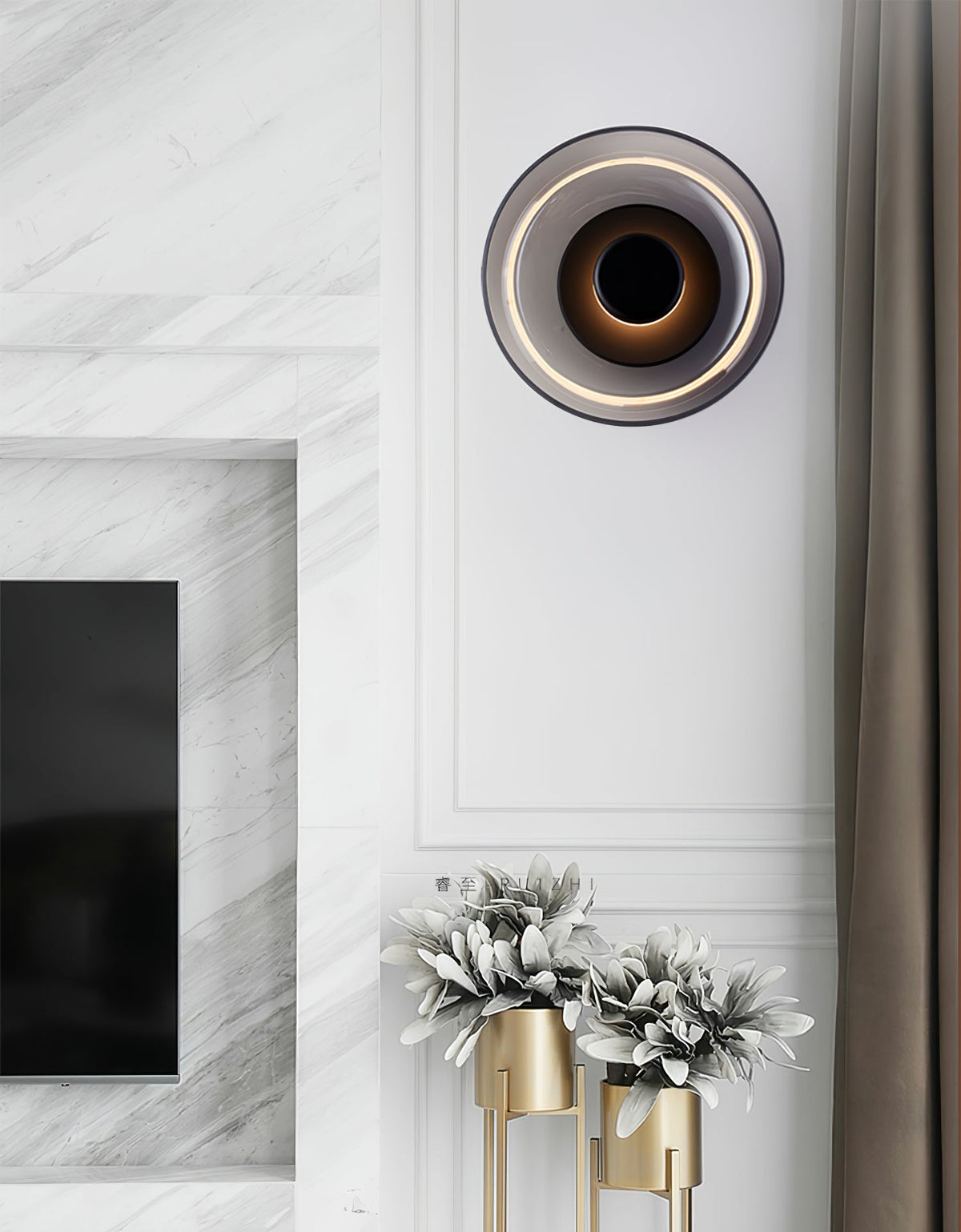 A smoke grey glass Clérachic wall light with a black body glows beside a grey curtain, above a marble fireplace and gold vases.