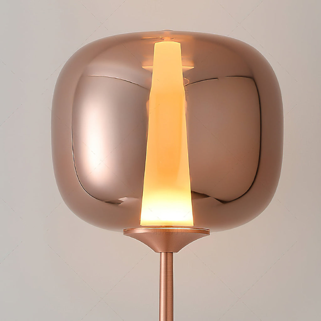 Close view of the rounded glass head and glowing light strip on a rose gold Clérachic floor lamp.