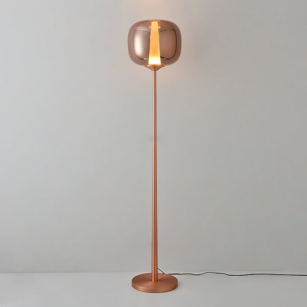 Lit rose gold Clérachic floor lamp with a glowing strip of warm light in its glass head, against a pale grey wall.