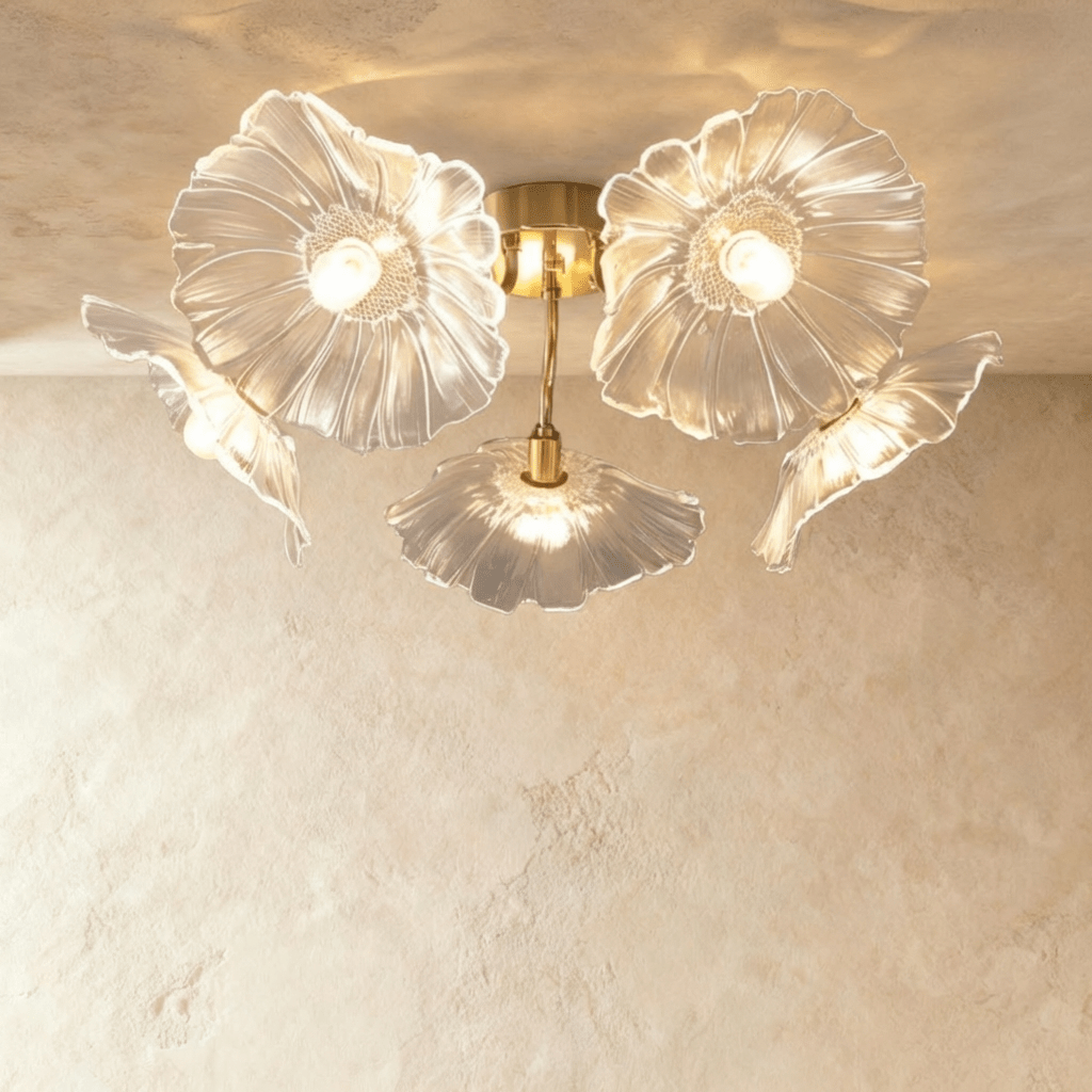 Clérachic five-head ceiling light with clear ribbed glass flower shades on curved brass arms, lit warm against plaster.