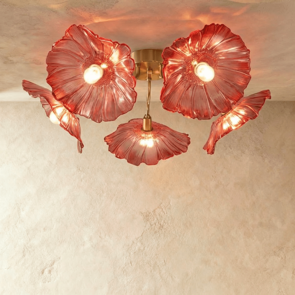 Clérachic five-head ceiling light with red ribbed glass flower shades glowing warm on curved brass arms.