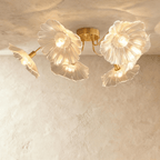 Clérachic six-head ceiling light with frosted clear glass flower shades on sweeping brass arms, seen from below.