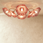 Clérachic six-head ceiling light with red glass flower shades fanned out on slim brass arms, glowing warm.