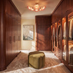 Clérachic red-toned glass flower ceiling light hung in a walnut-panelled dressing room above an olive velvet pouffe.