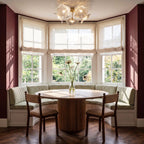 Clérachic clear glass flower ceiling light over a round fluted dining table in a bay window with linen blinds.