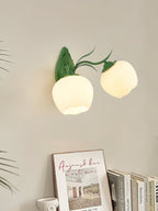 Two opal glass shades on a green Clérachic double wall light, hung above a shelf with books and a framed print.