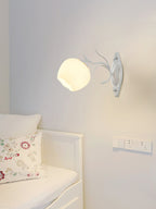 Single white Clérachic wall light with a rounded glass shade on a pale grey wall above a white daybed.