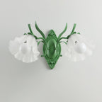 Unlit green Clérachic double wall light with two frosted flower shades and white bulbs, on a light grey wall.