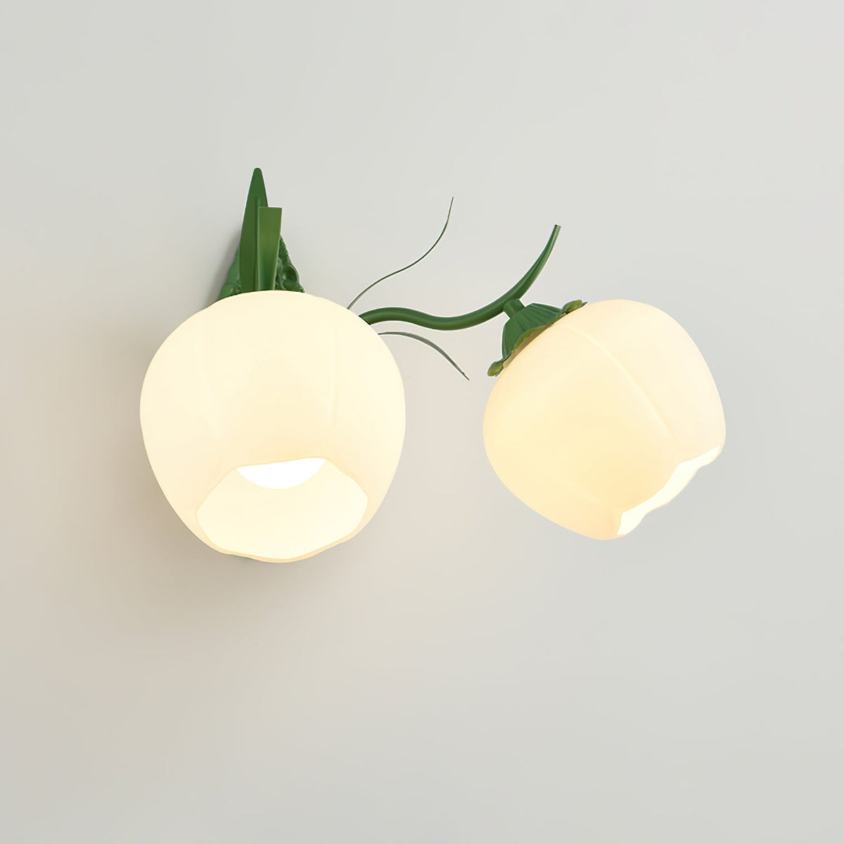 Two lit opal glass shades on a thin green arm of this Clérachic wall light, shown on a light grey wall.