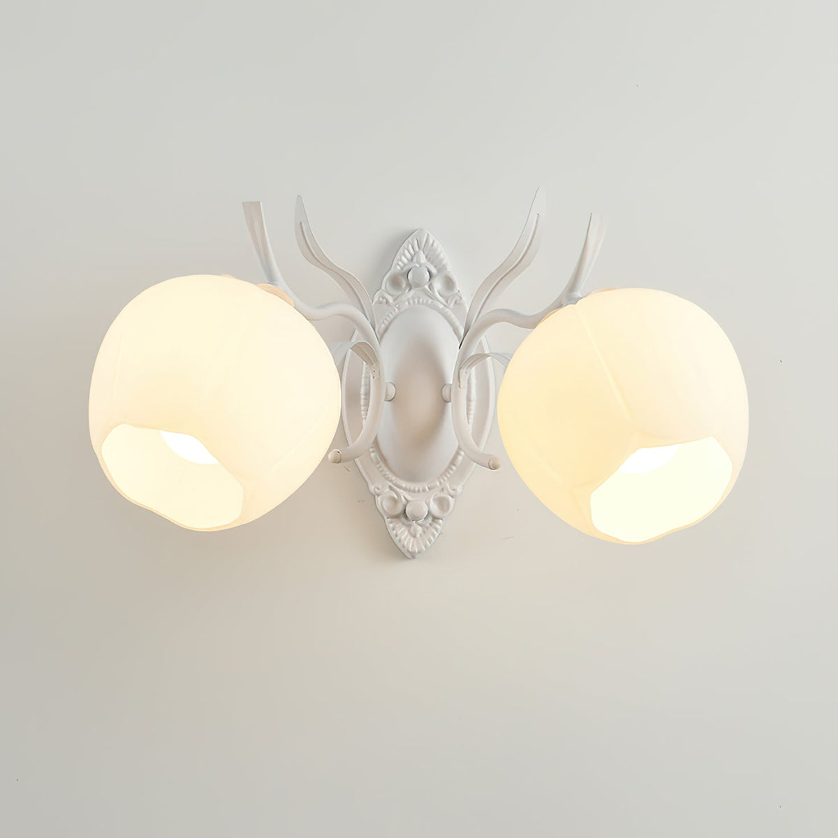 Lit white Clérachic double wall light with two rounded opal shades, seen against a pale grey wall.