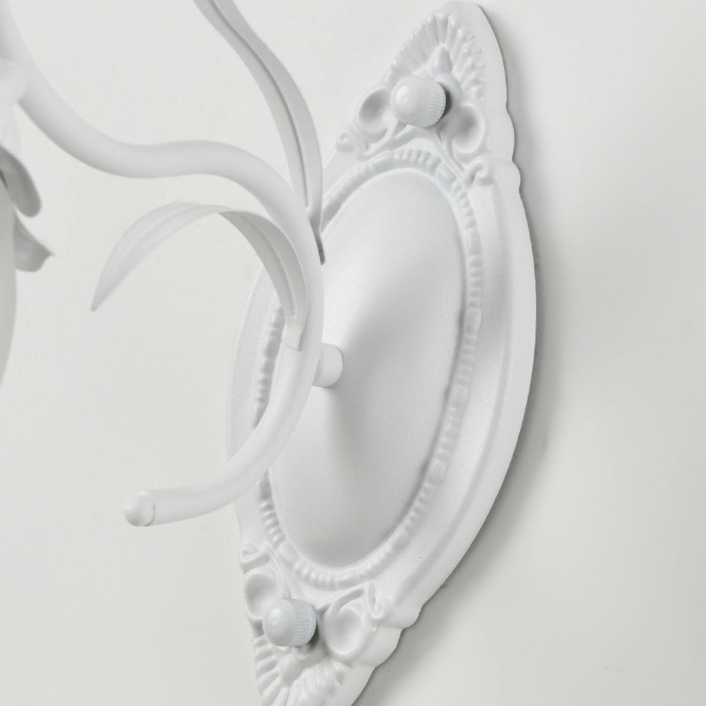 Close view of the carved oval backplate and curved white arm of this Clérachic wall light.