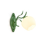 Green Clérachic wall light with a round opal glass shade and a carved oval backplate, seen from the side.