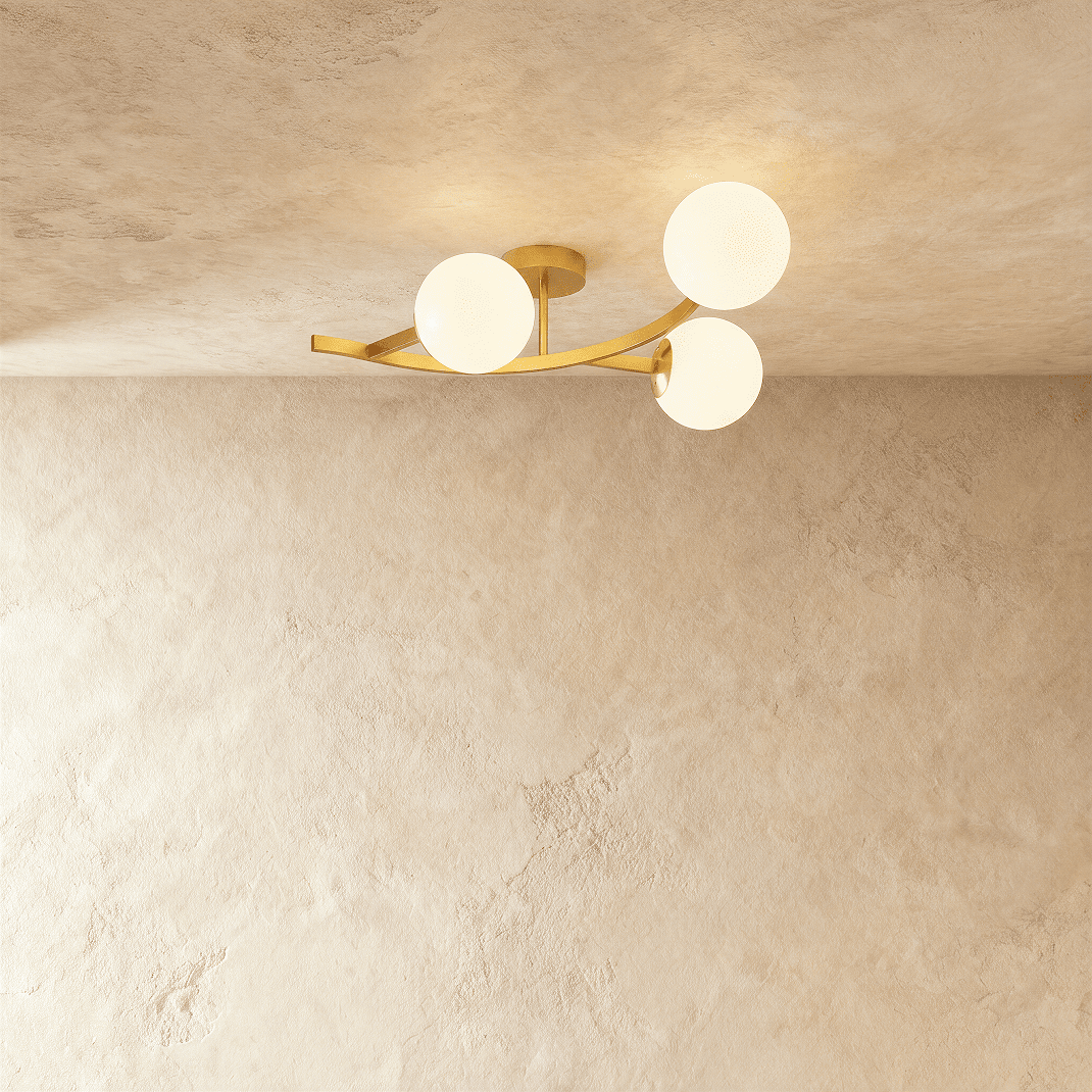 Clérachic three-globe ceiling light on a curved gold arm with opal white glass globes, lit against plaster.